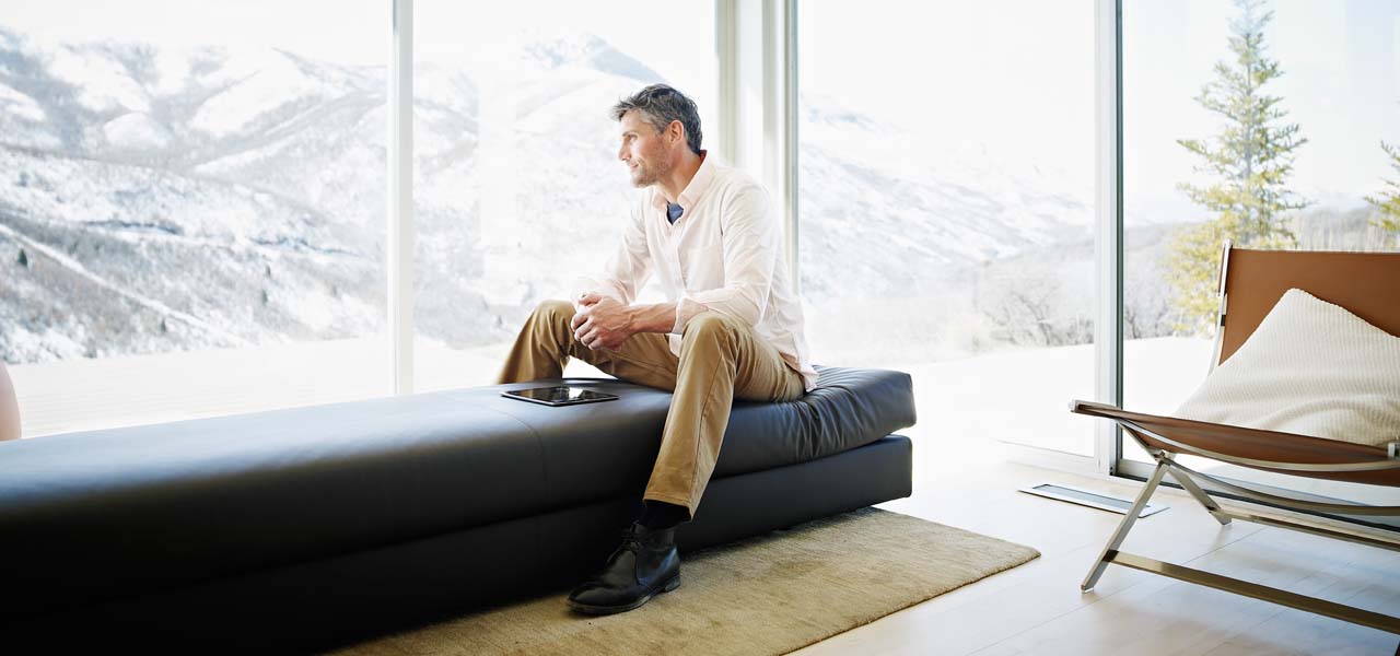 Ein Mann sitzt auf der Couch und blickt nach draußen in die Natur.
