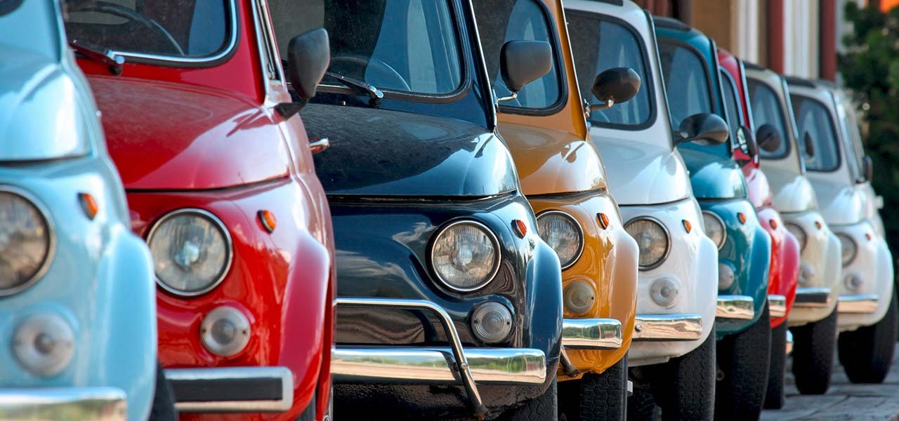 Eine ganze Reihe von alten Fiat 500 in verschiedenen Pastellfarben.