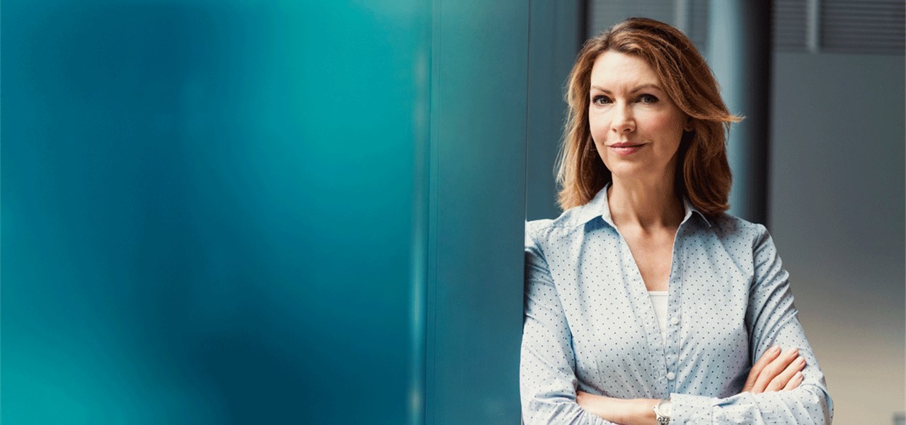 Eine Businessfrau lehnt sich an eine Wand. 