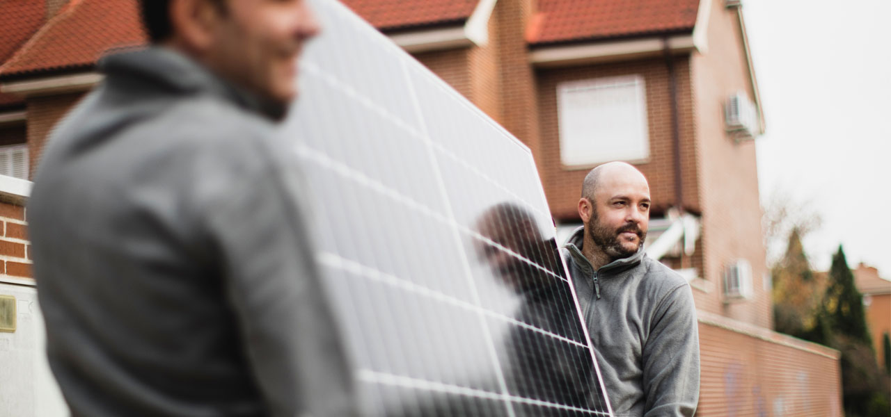 Zwei Männer tragen ein Solarpanel.