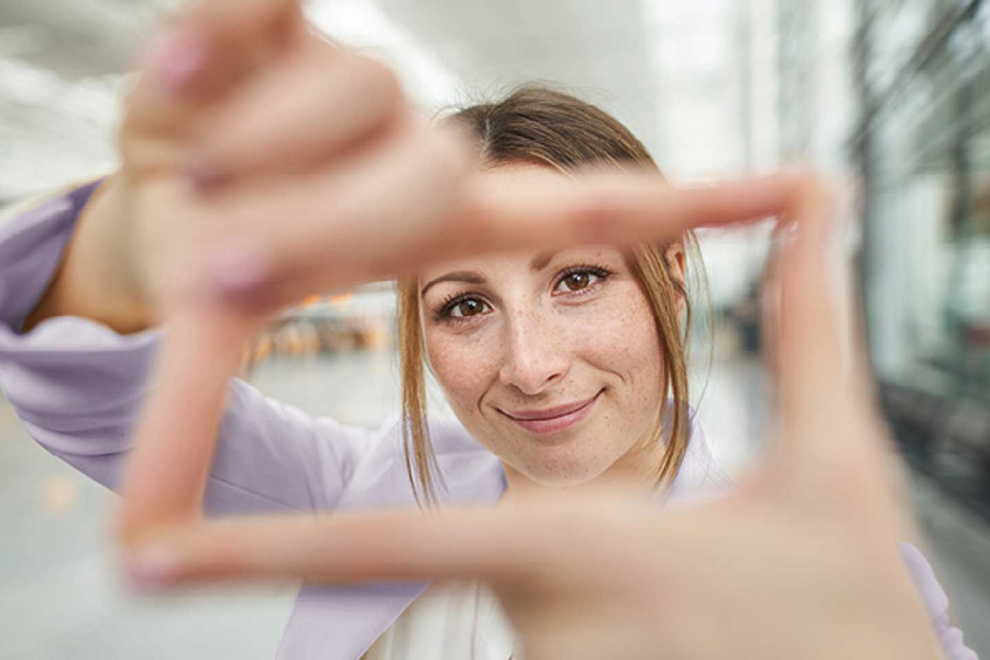 Eine lächelnde Frau bildet mit ihren Fingern einen Rahmen.