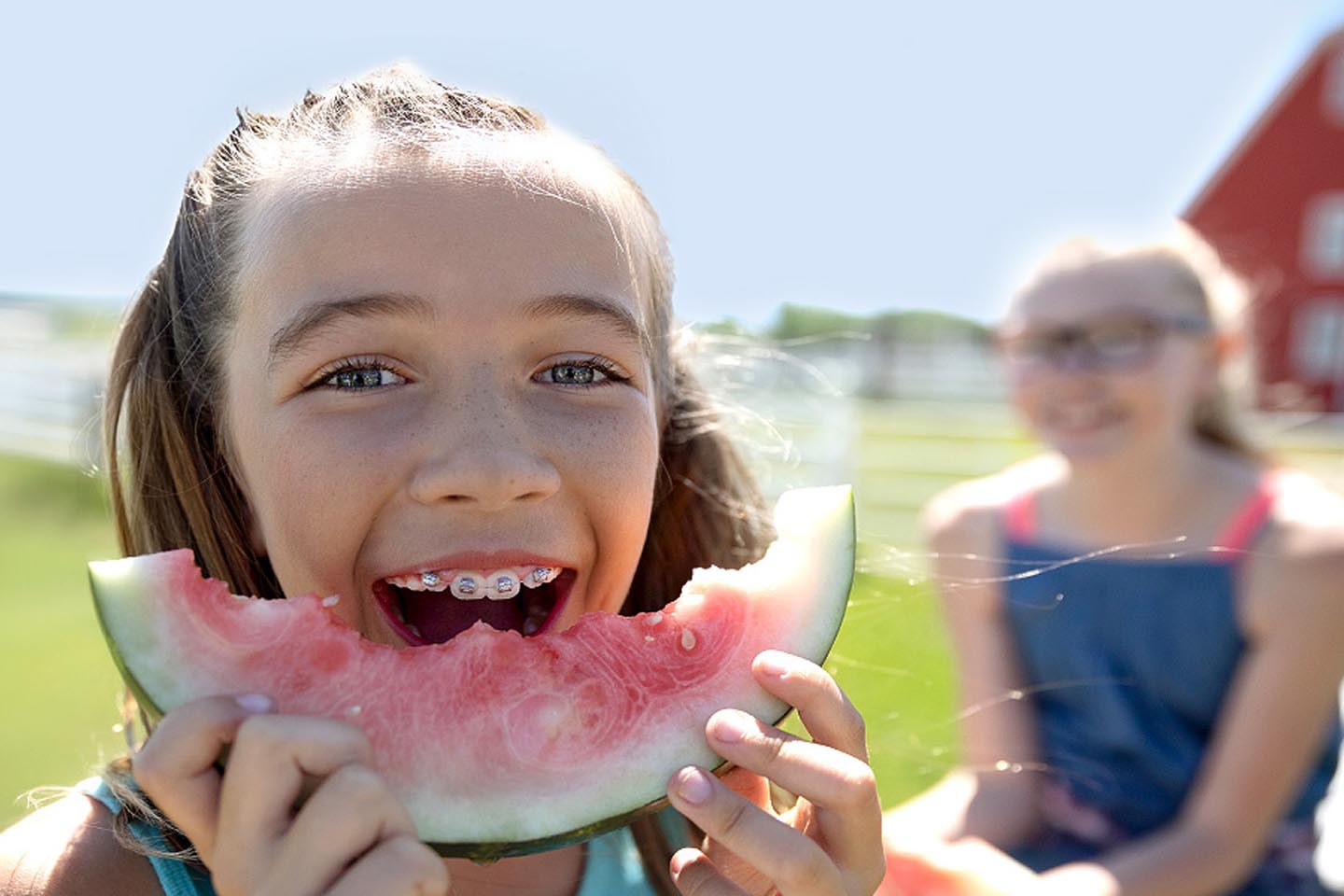 Ein Mädchen mit Zahnspange beißt in eine Wassermelone.
