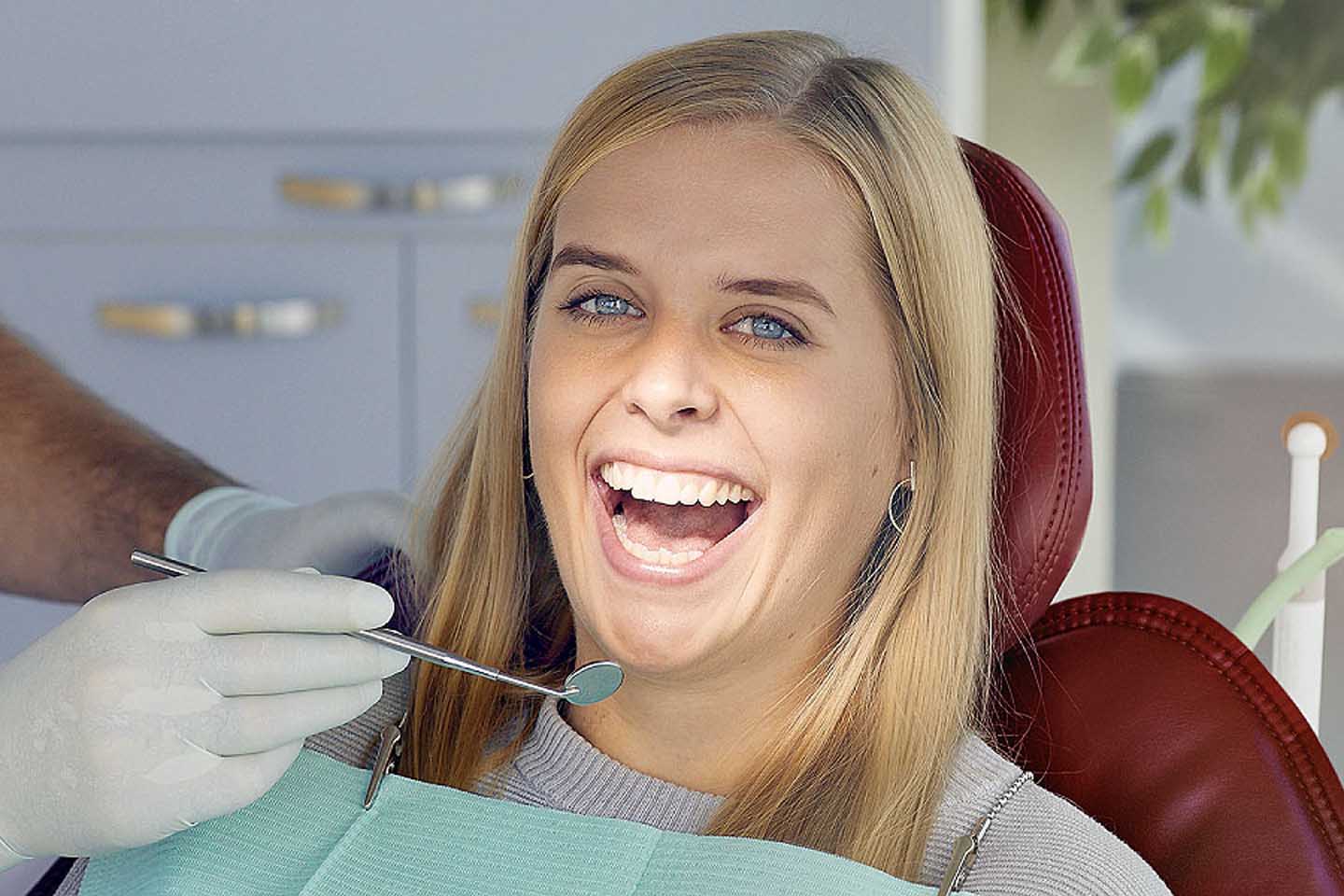 Eine Frau auf einem Zahnarztstuhl wird untersucht. 