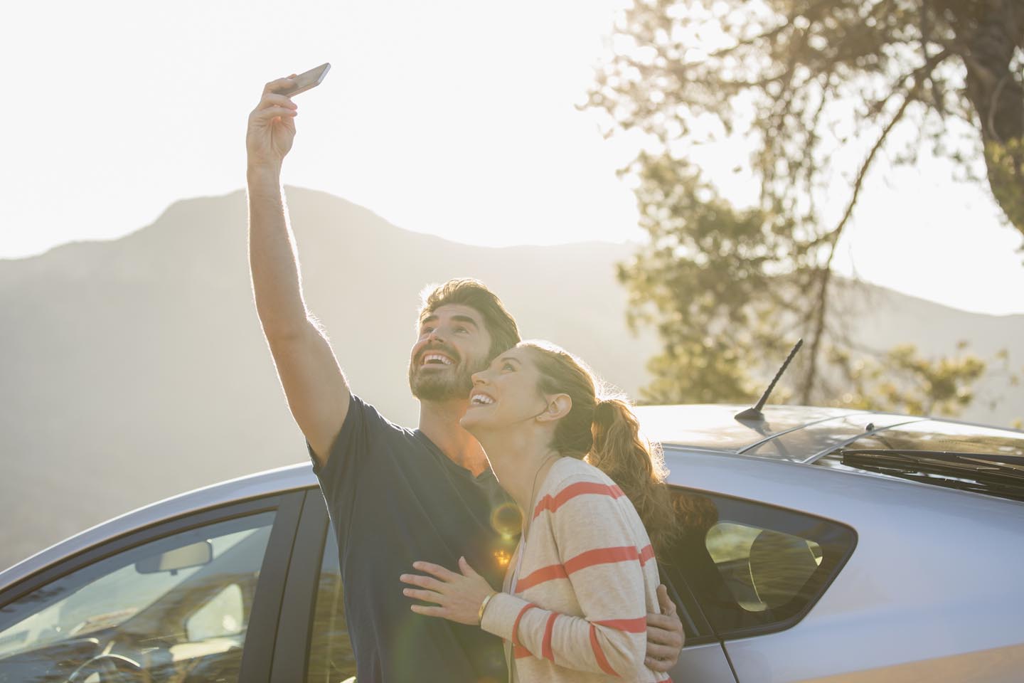 Junges Paar macht ein Selife am Auto.