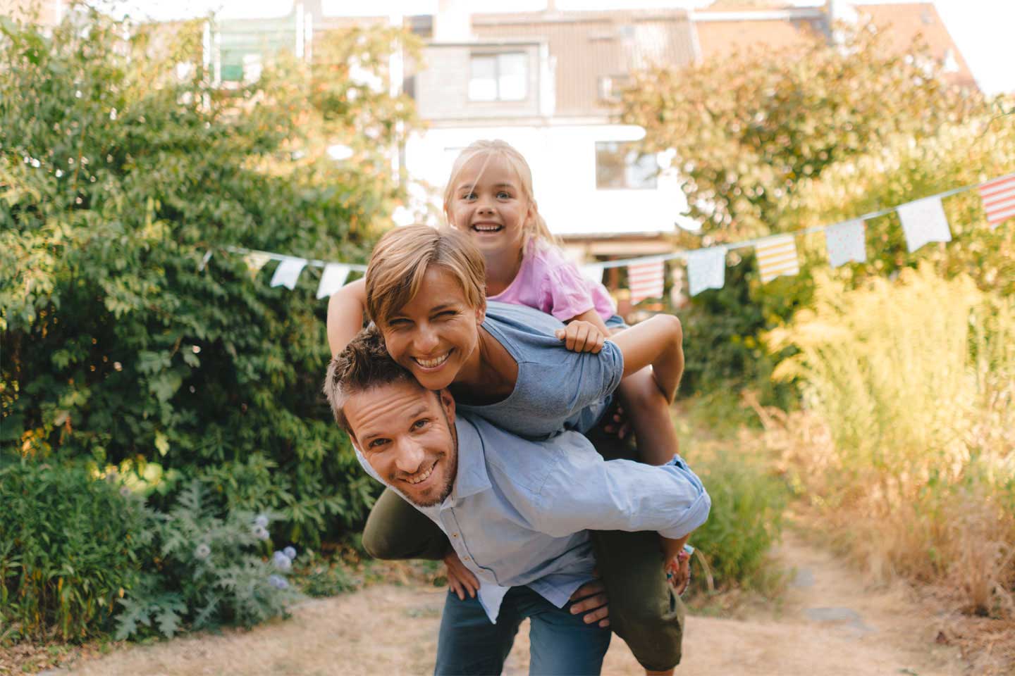 Happy father carrying family piggyback in garden