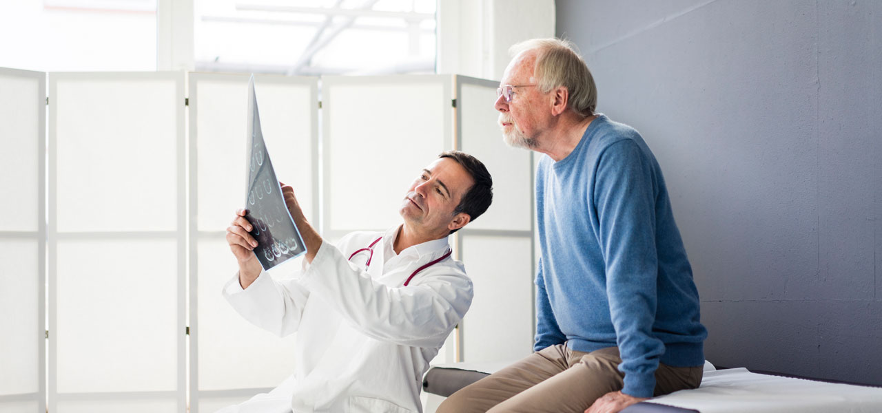 Ein Arzt bespricht mit einem älteren Patienten dessen Röntgenbild.