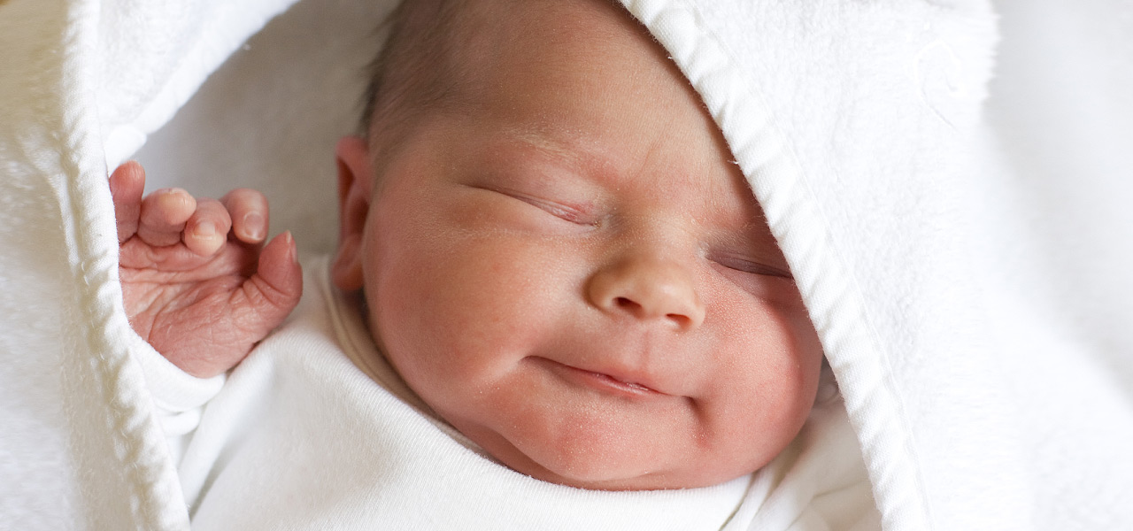 Ein Neugeborenes ist in eine weiße Decke gehüllt.