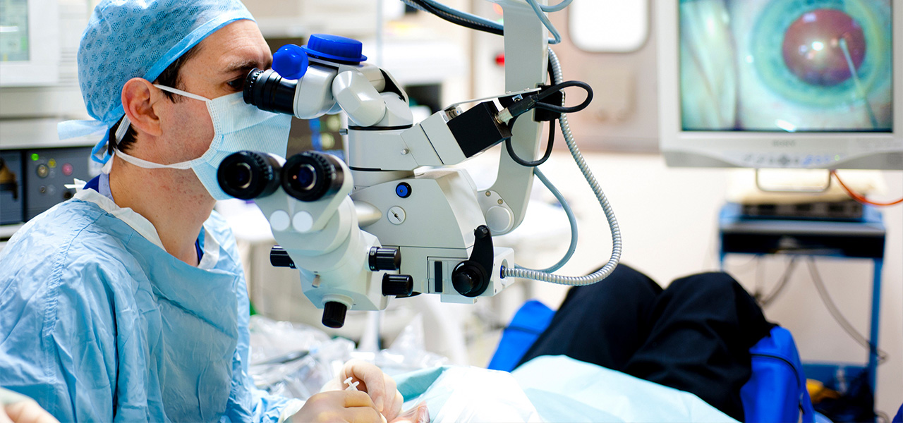 Ein Augenchirurg führt eine OP durch. Dazu nutzt er ein medizinisches Mikroskop.