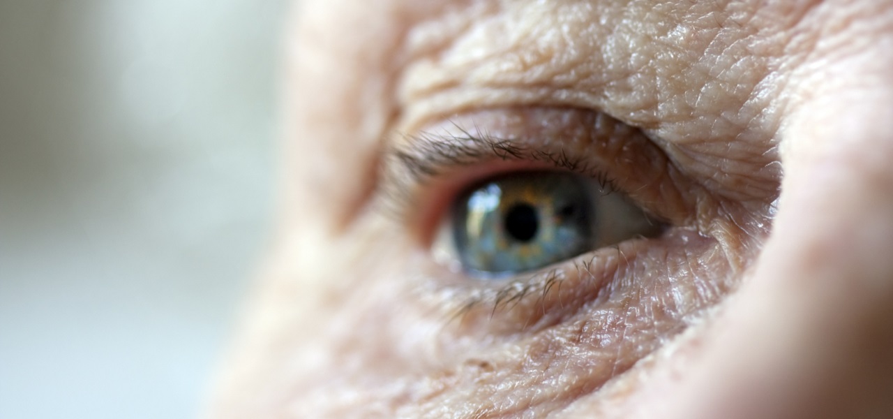Ein Auge einer älteren Person mit Falten in der Nahaufnahme.