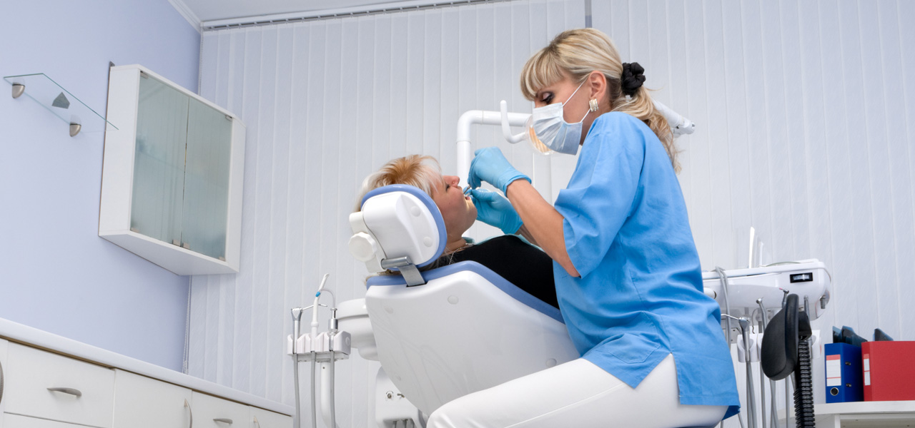 In einer Zahnarztpraxis führt eine Zahnärztin die Kontrolle bei Ihrer Patientin durch. 