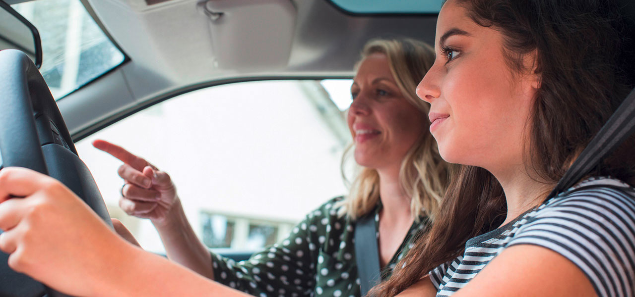 Zwei Frauen sitzen im Auto. Die Beifahrerin zeigt der Fahrerin den Weg.