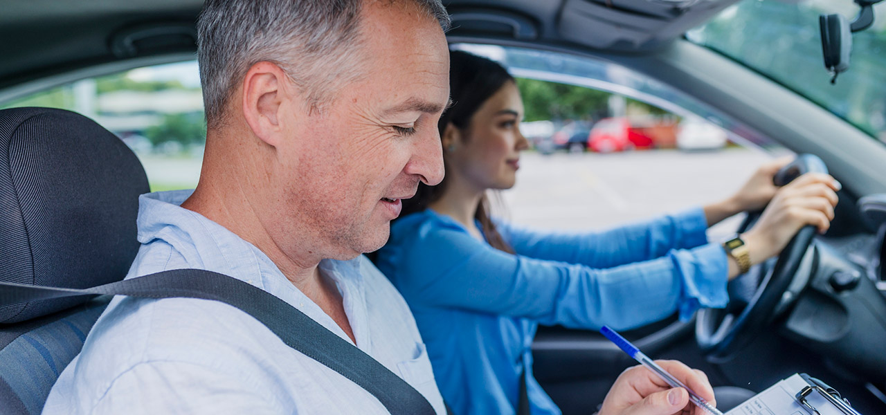 Ein Fahrprüfer bewertet eine junge Dame bei Ihrer Prüfung. Sie sitzen zusammen im Auto.