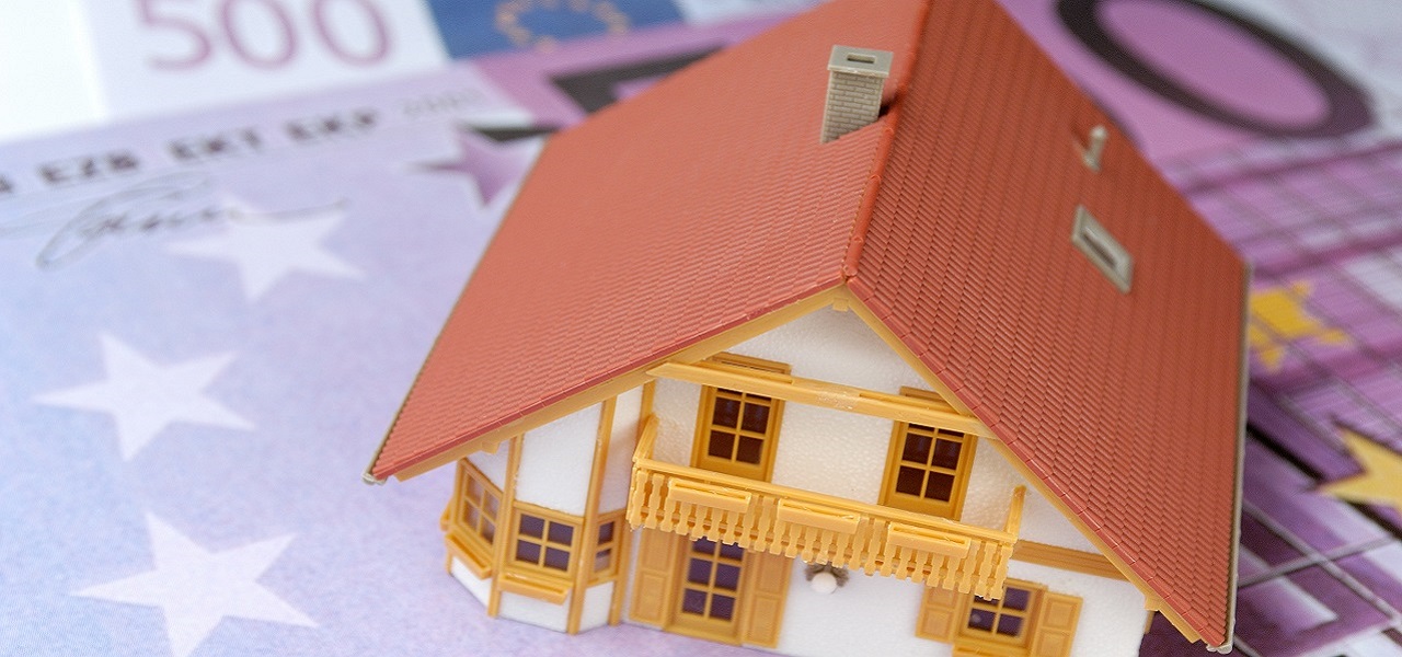Ein Modelhaus als Miniatur steht auf einem 500 Euro-Schein.