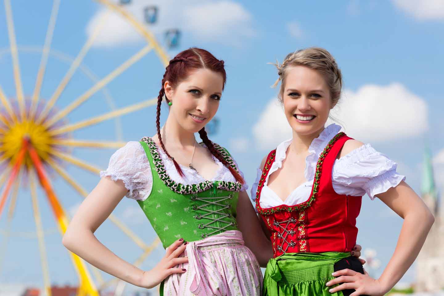 Zwei Frauen im Dirndl vor einem Riesenrad.