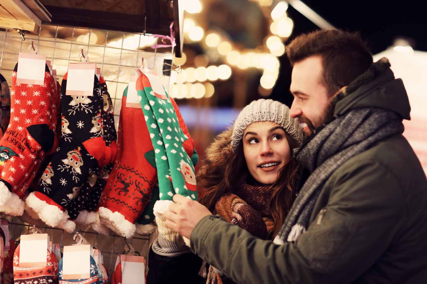 Ein Paar ist auf dem Weihnachtsmarkt und schaut sich Socken an.