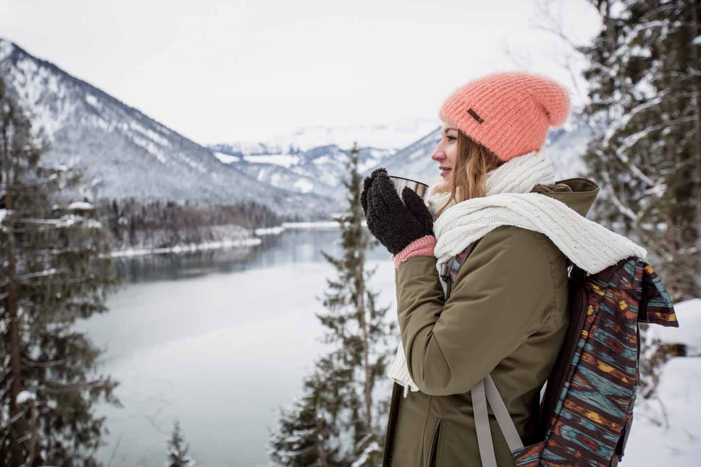 Frau steht an einem Bergsee im Winter
