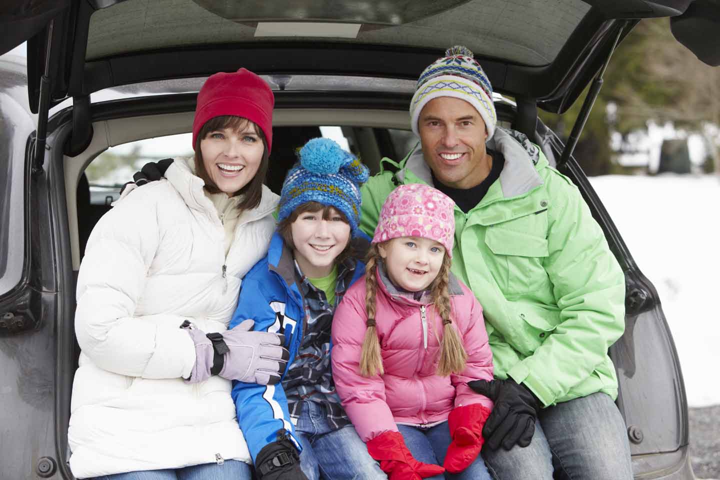 Eine Familie ist im Winter an dem Auto.