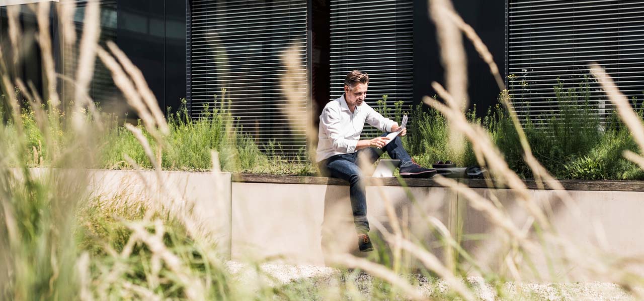 Ein Mann sitzt draußen vor einem Gebäude und liest.