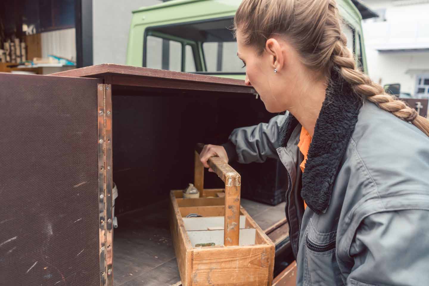 Eine Frau verlädt einen hölzernen Werkzeugkasten in eine Kiste. 