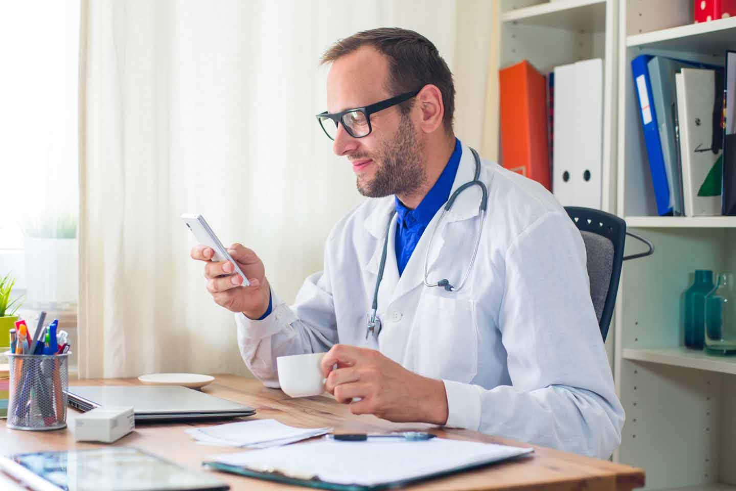 Ein Arzt tippt eine Notiz in ein Smartphone.