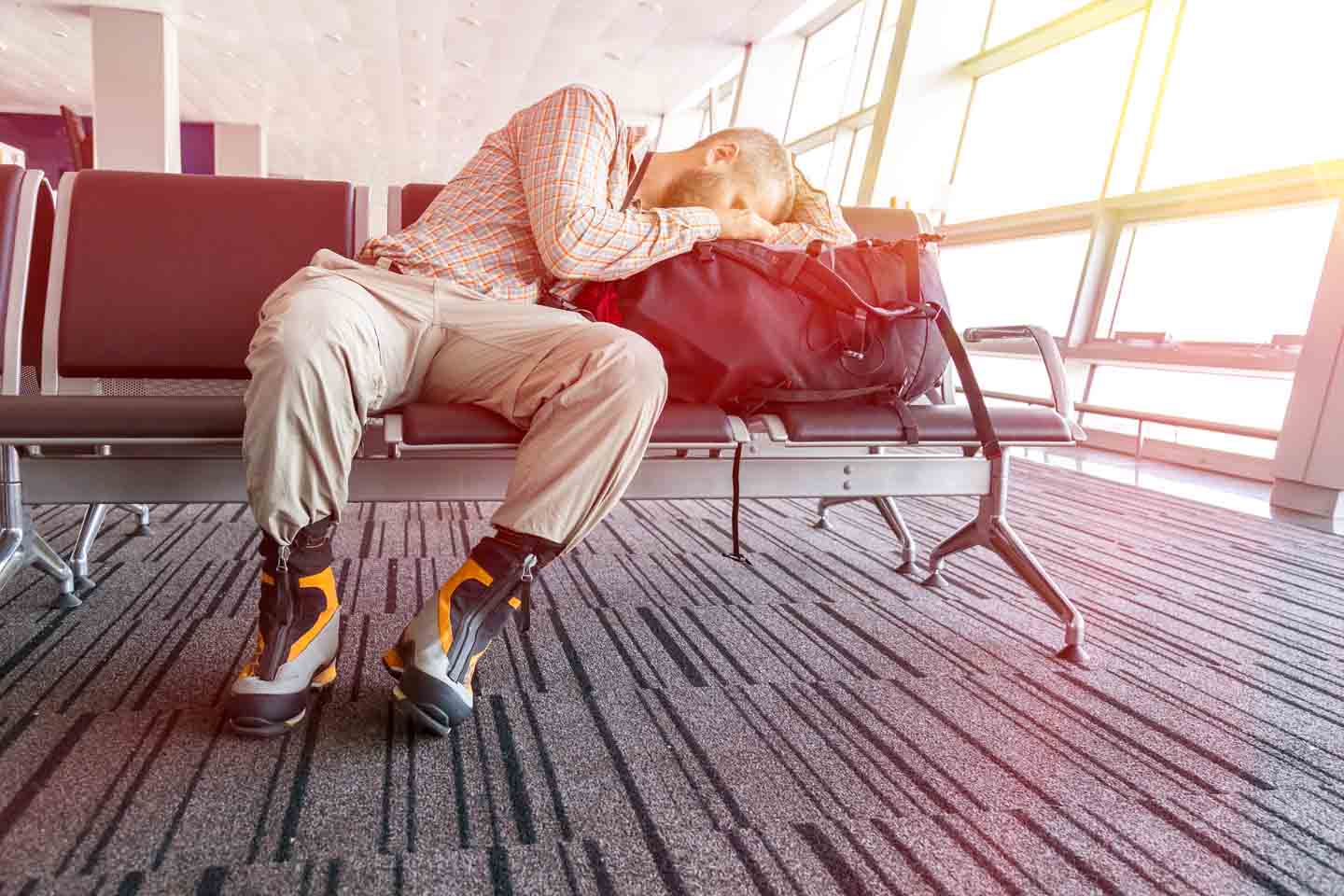 Mann schläft im Flughafen mit Kopf auf seiner Reisetasche