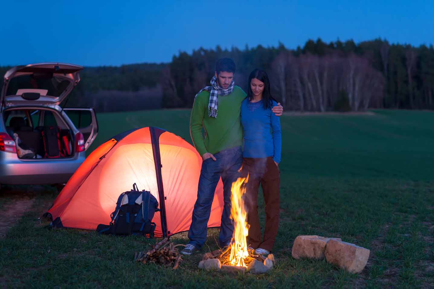 Ein junges Paar steht vor einem Lagerfeuer.