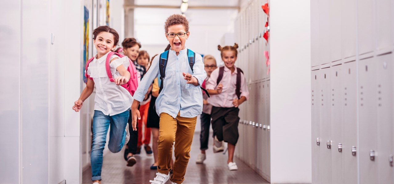 Schulkinder rennen fröhlich den Gang entlang. 