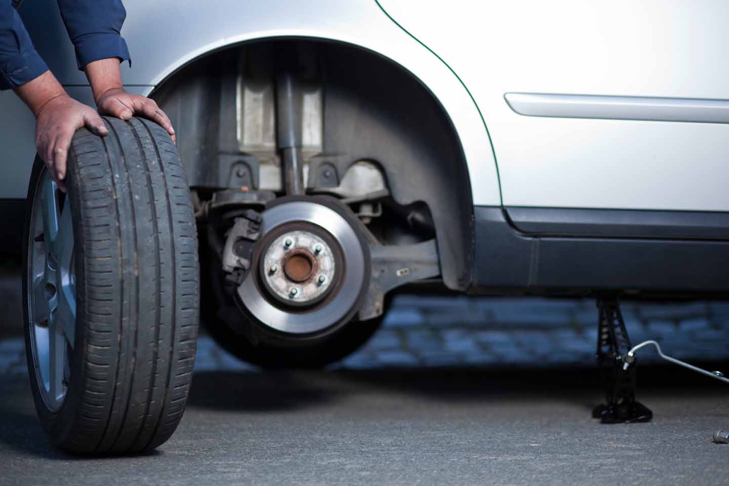 Der Mechaniker wechselt ein Rad vom Auto.