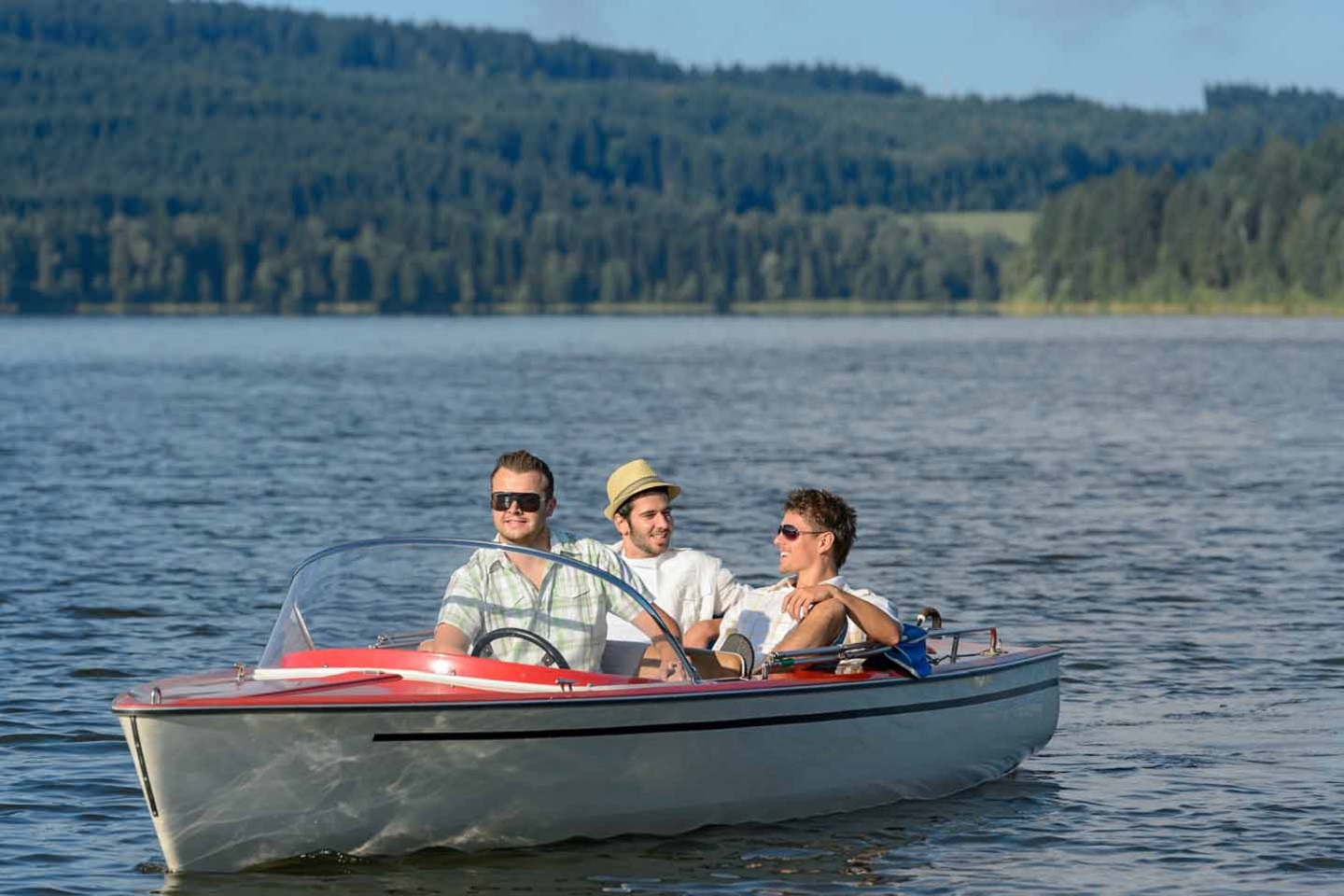 Drei junge Männer fahren in einem kleinen Motorboot.