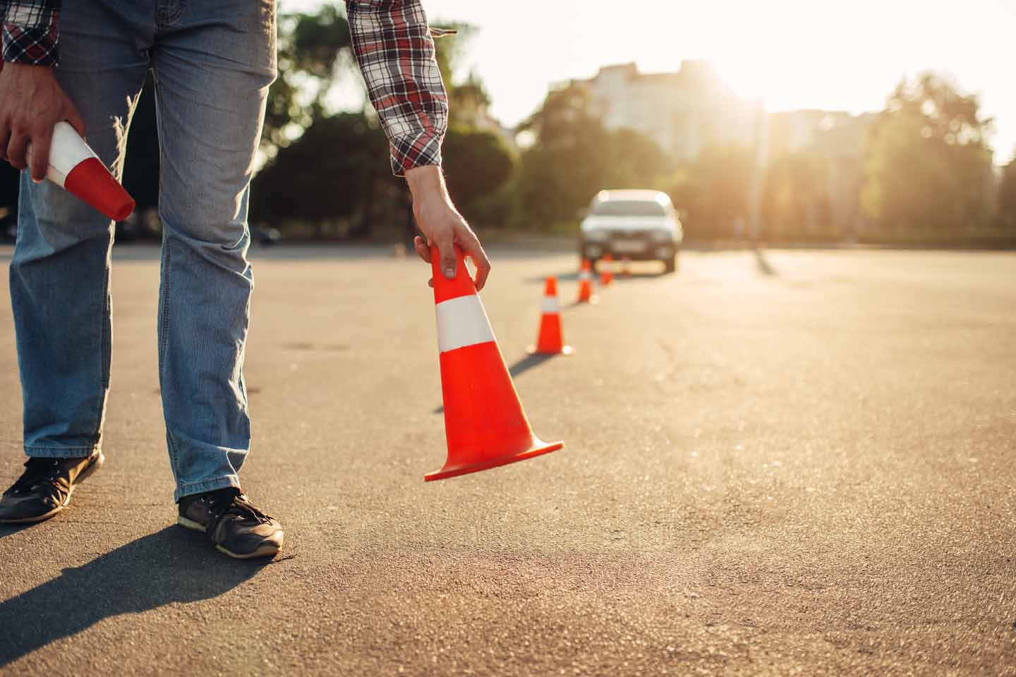 Für einen Fahrsicherheitstest werden Pylonen auf der Straße aufgestellt. Im Hintergrund ist ein Auto zu sehen. 