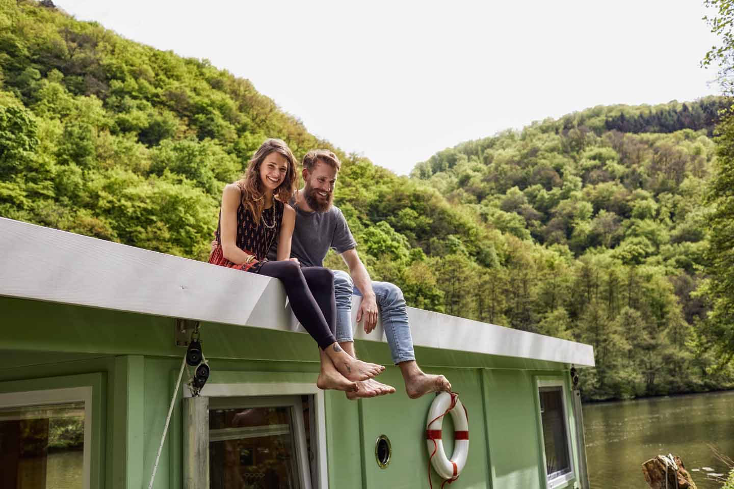 Ein junges Paar sitzt auf einem Hausboot.