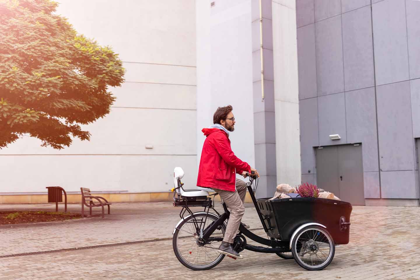 Ein Mann auf einem Lastenrad hat einen Kindersitz auf dem Gepäckträger.