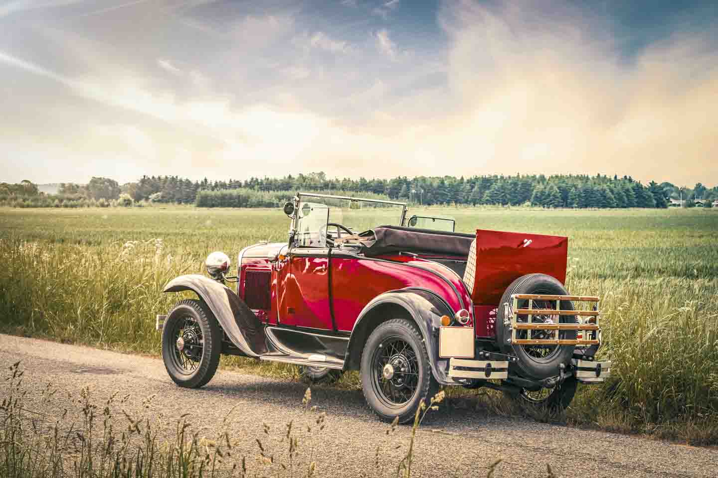 Ein roter Oldtimer steht am Straßenrand.