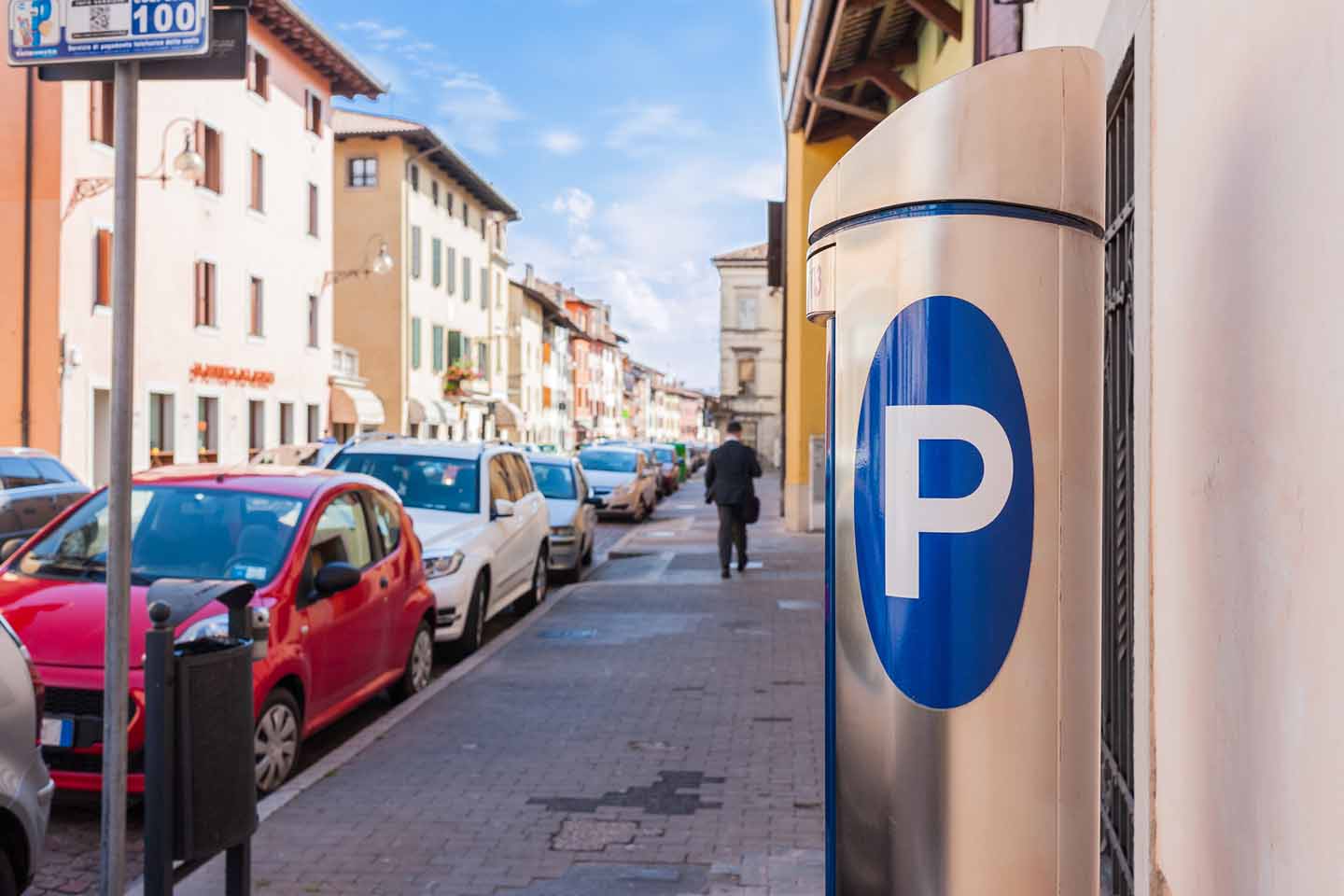Ein Parkscheinautomat an einer voll geparkten Straße in der Stadt.