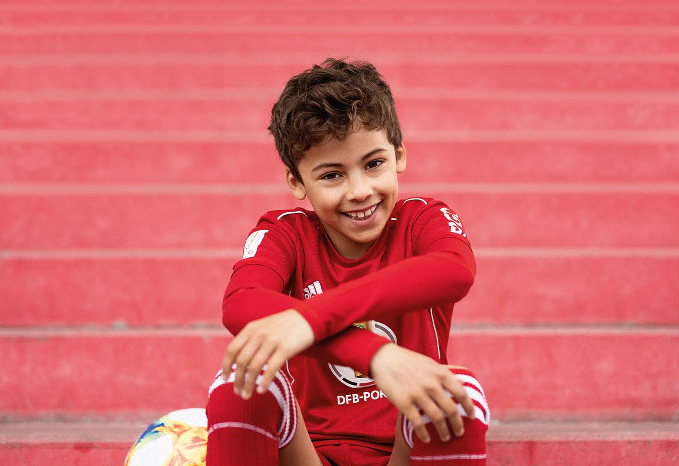 Ein Junge im Fußballtrikot lächelt in die Kamera.