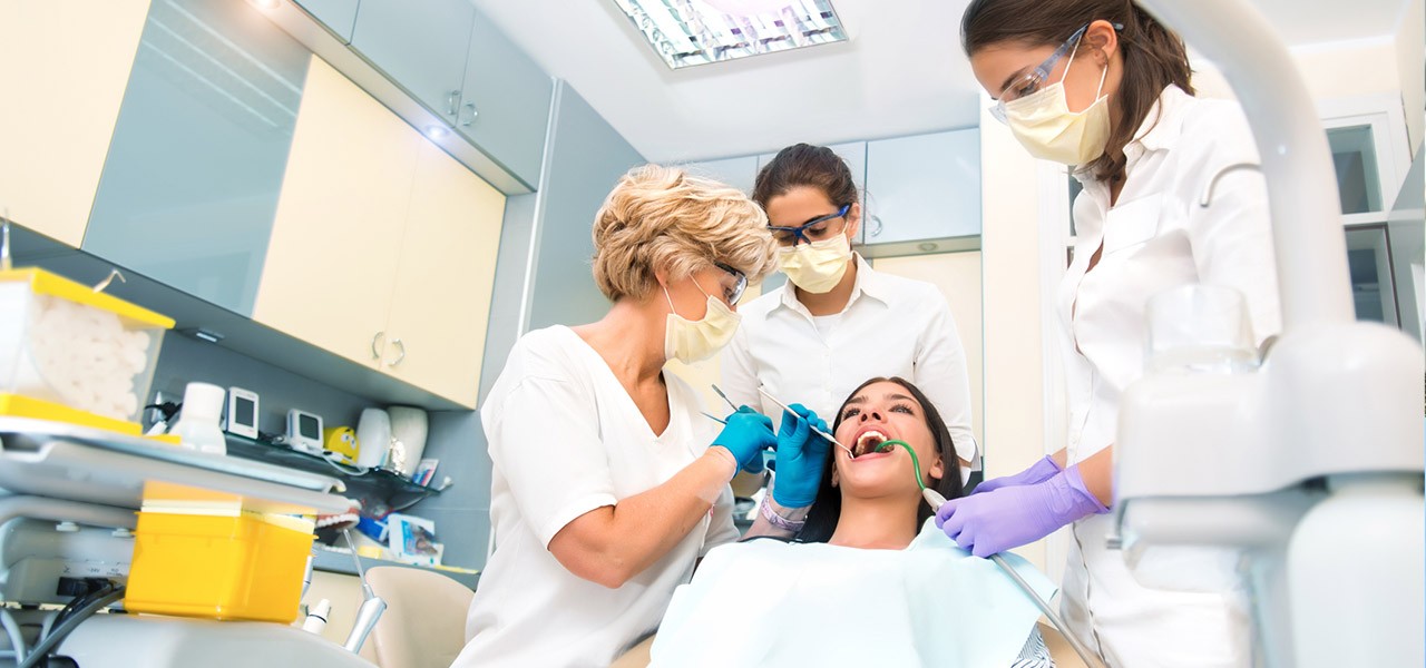 In einer topmodernen Praxis behandeln Zahnärzte gemeinsam eine Patientin.