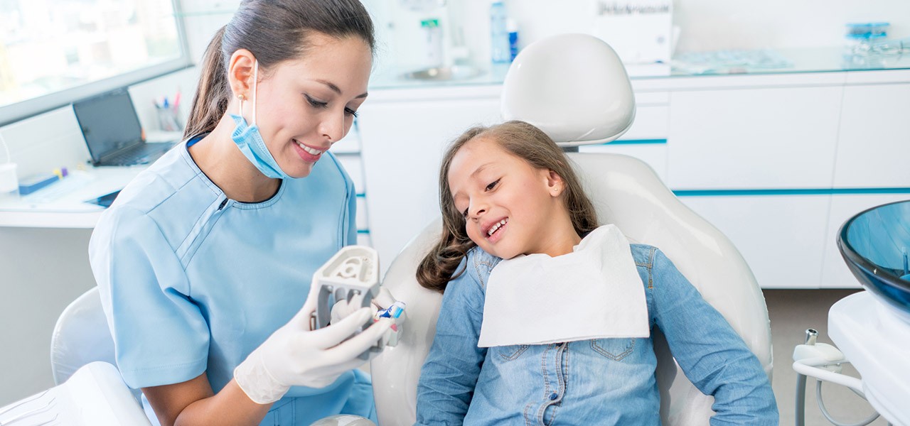Eine Zahnärztin erklärt einem jungen Mädchen die anstehende Behandlung.