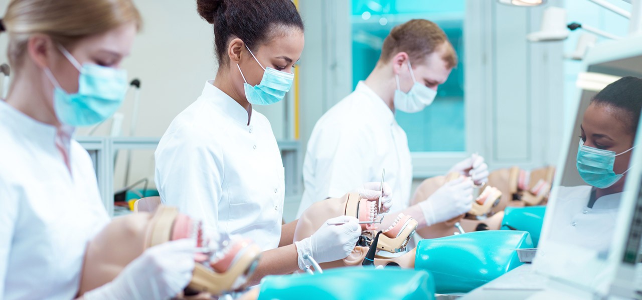 Drei Zahnmediziner üben Behandlungsmethoden unter Laborbedigungen.