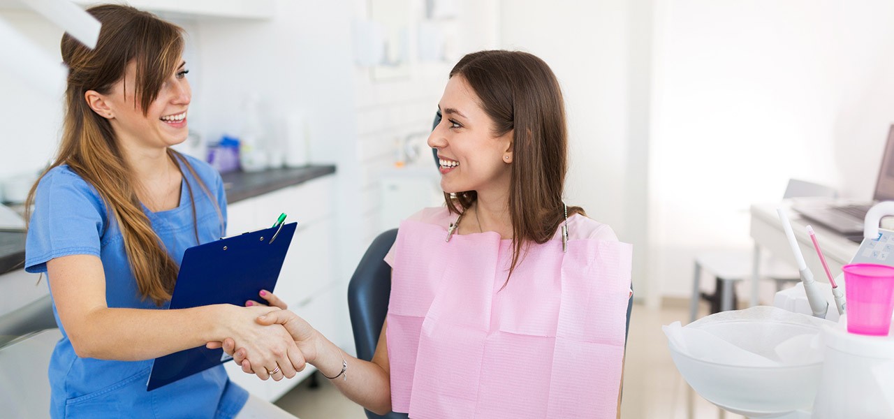Eine Zahnärztin begrüßt Ihre Patientin mit Handschlag. Die Stimmung ist gelöst.