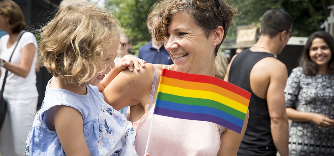 Tochter mit Regenbogenflagge auf dem Arm der Mutter