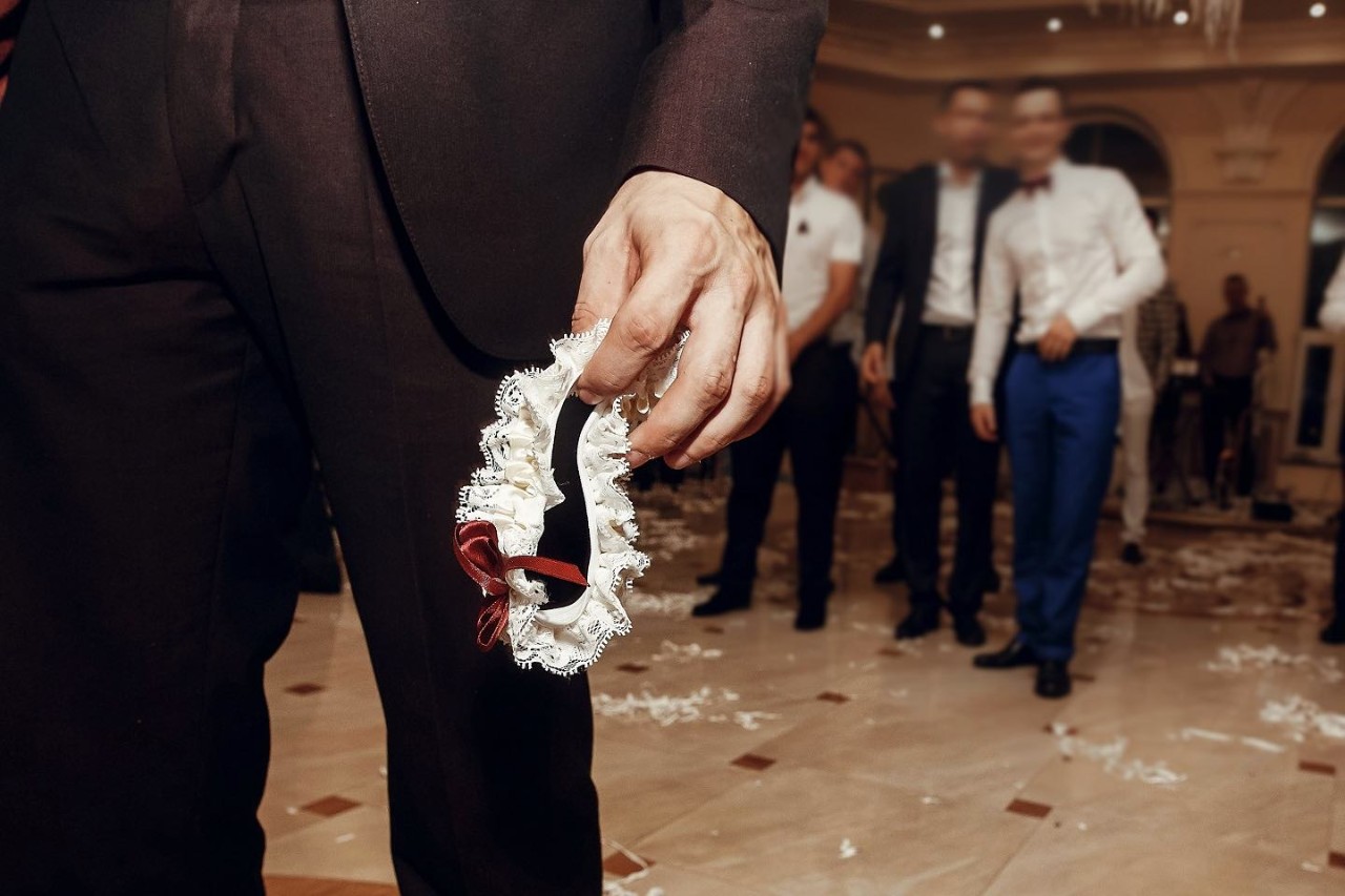 Eine Männerhand eines Mannes, der Anzug trägt, hält ein Strumpfband.