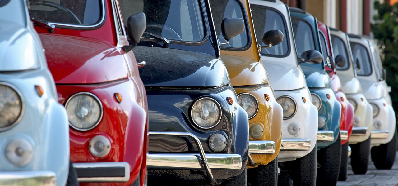 Eine ganze Reihe von alten Fiat 500 in verschiedenen Pastellfarben.
