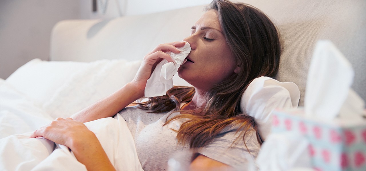 Frau liegt mit einer Erkältung im Bett