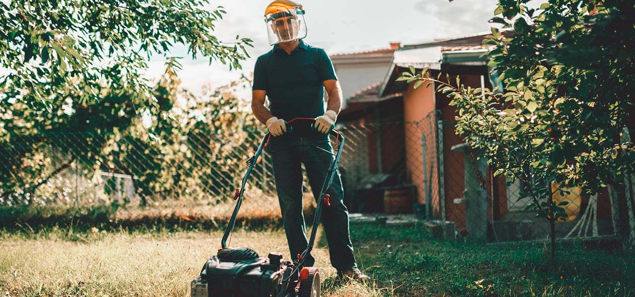 Sicherheit im Garten: Gärtner trägt Schutzausrüstung beim Rasenmähen