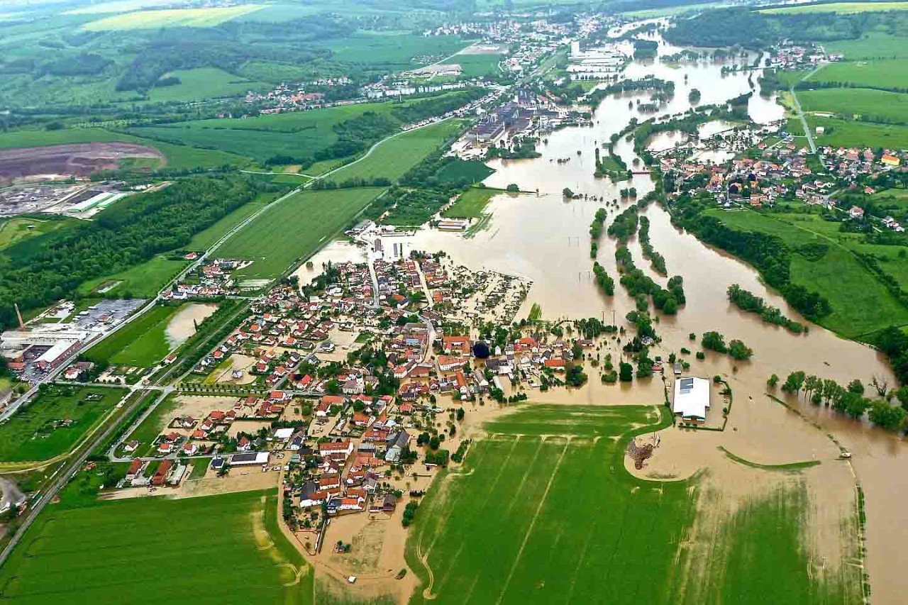 Luftbild einer überschwemmten Ortschaft.