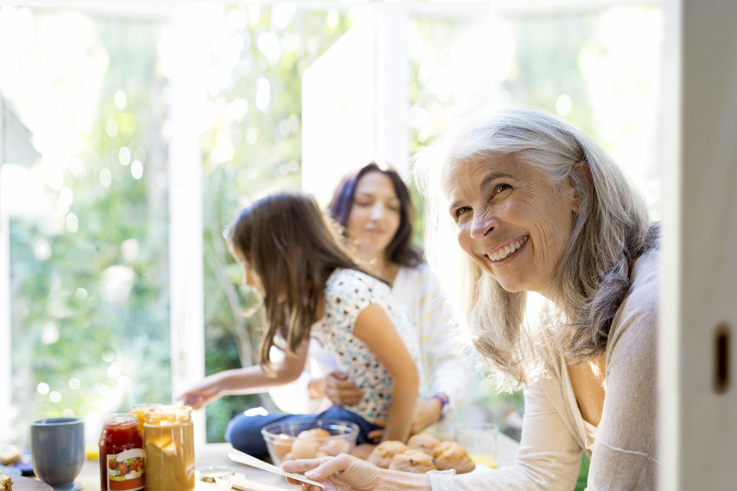 Lachende ältere Frau mit jungem Mädchen und ihrer Mutter in der Küche.